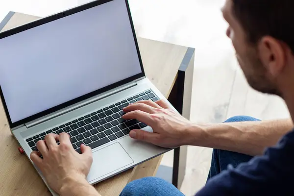 Günlük tarzda giyinen, kot giyen, oturan ve yazan, beyaz ekranın önünde, kot pantolonlu, küçük bir masada, açık renkli bir resimde, çevrimiçi derste veya çevrimiçi toplantıda, kafede ya da ofiste.