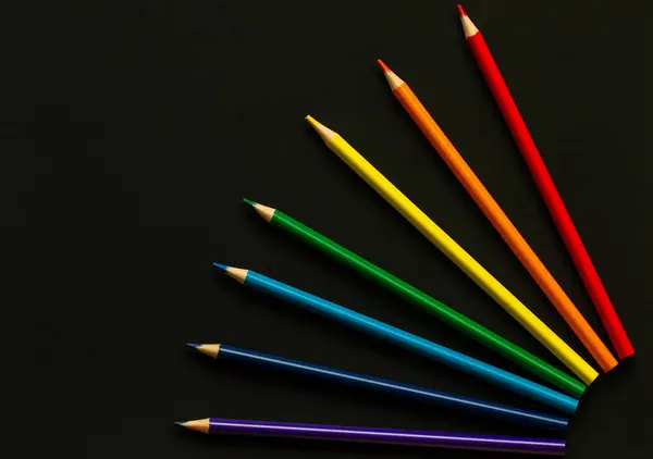 Sade arka planda parlak okul malzemeleri. Renkli kırtasiye malzemesi, kalem, renkli kalem seti, koyu arkaplanda gökkuşağı renk sırası