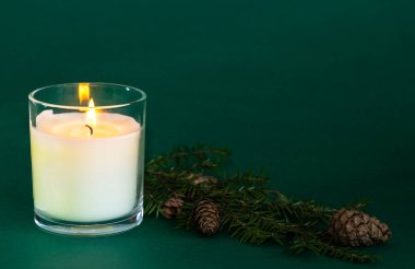 Yeşil arka planda mum ve doğal çam kozalakları, orman ve çam iğneleri aroması, Noel ve yeni yıl aroması