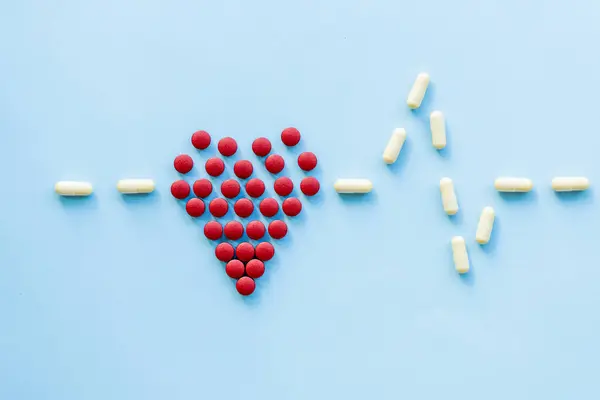 Sağlıklı kalp, kalp hastalığı ve benzeri konularda soyut. Parlak mavi arka planda kalp şeklinde parlak kırmızı haplar.