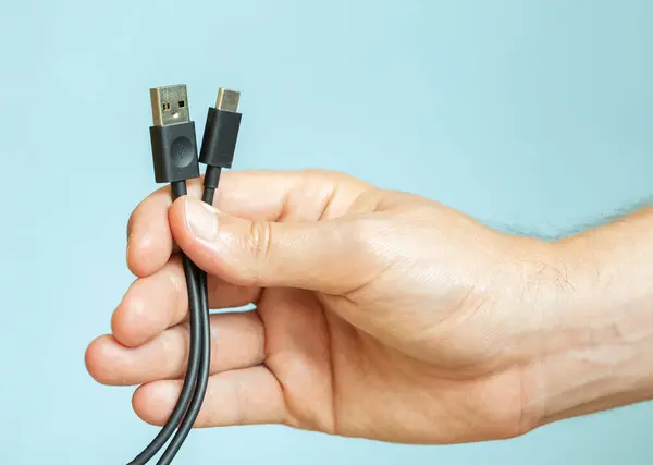 Elinde birkaç kablo tutan adam, farklı türde USB kablolar, teknoloji ve bağlantı konsepti