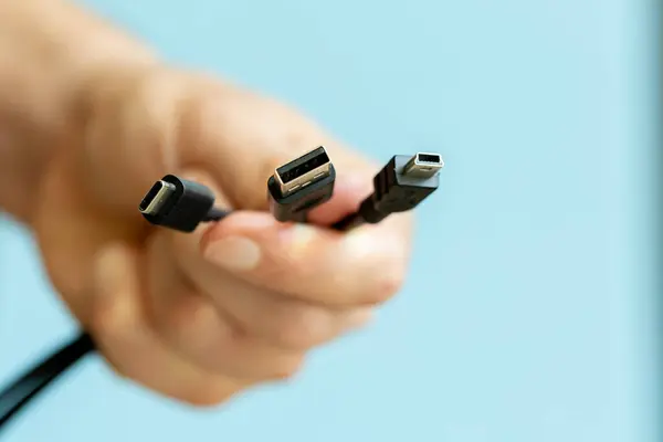 Elinde birkaç kablo tutan adam, farklı türde USB kablolar, teknoloji ve bağlantı konsepti