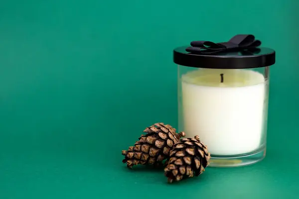 Yeşil arka planda mum ve doğal çam kozalakları, orman ve çam iğneleri aroması, Noel ve yeni yıl aroması