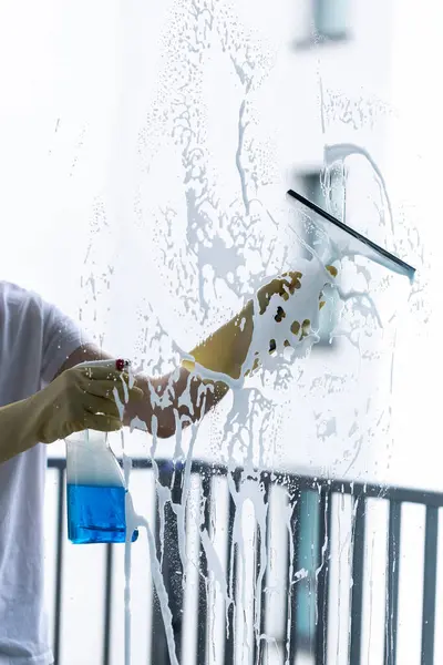  Beyaz gömlekli ve sarı eldivenli bir adam pencereyi temizliyor.