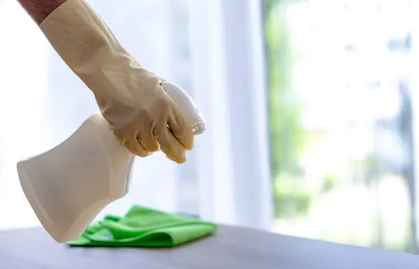 Temizlik spreyi, sarı güvenlik eldiveni ve mikrofiber bez ile toz alma. İç mekan temizliği, pencere arkası