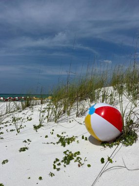 Sahilde beyaz kum tepelerinde renkli bir plaj topu. 