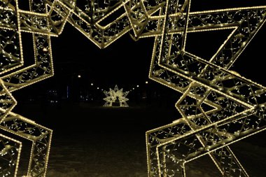 Noel ışıkları karla ve ağaçlarla süslenmiş.