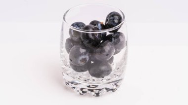 Beyaz Arkaplanda Şeffaf Cam Kupada Taze Siyah Üzümler