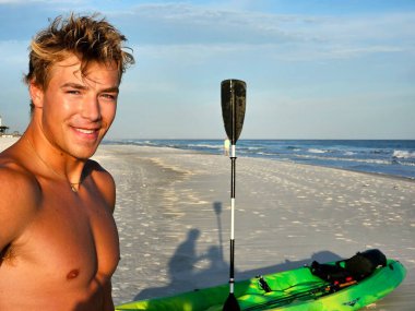 Kumsalda tişörtsüz milenyum, denize kanoyla açılmaya hazır..