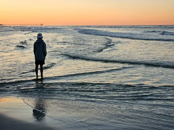 Siluetli turist okyanusta durup tatilde güneşin doğuşunu seyrediyor.. 