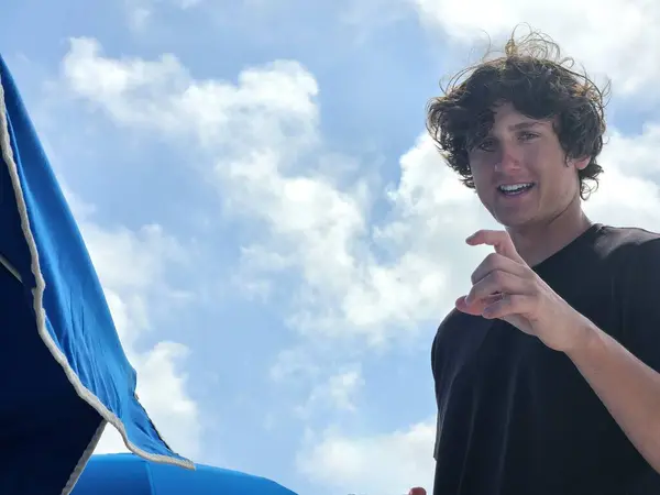 Genç adam Millennial kumsalda parmaklarını kullanarak ölçü alıyor..