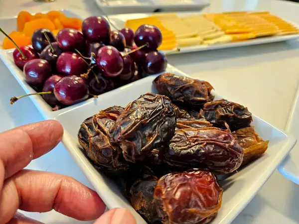 Masa üstü yiyecekler, hurma, kiraz, kayısı ve peynirli bir partide atıştırmalık yiyecekler sunar..