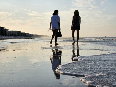 Siluetli milenyum arkadaşları Florida 'da sabah sörf yaparken sahilde çöp topluyor.. 