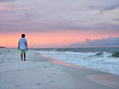 Minimalist sahil manzarası Florida 'da gün doğumunda deniz kıyısında yürüyen bin yıllık bir adamla. 