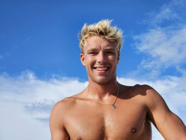 Kumsalda mavi gökyüzü geçmişi olan, tek renkli modeller olan mutlu yakışıklı adam.. 