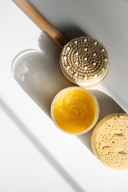 Sarı vücut fırçası, kuru masaj anti-selülit fırça ve sünger güneş tarafından aydınlatılmış beyaz arkaplan