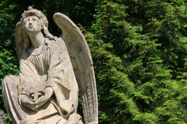 Elinde haçla gökyüzüne bakan bir meleğin heykeli.