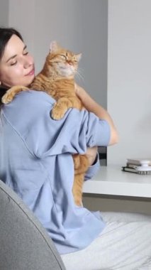 Evdeki sevimli kızıl kediyi okşayan kız.