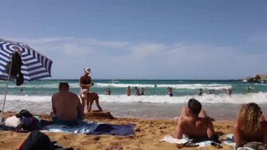 İnsanlar Malta 'daki Ghajn Tuffieha Körfezi' ndeki Riviera plajında vakit geçiriyorlar.