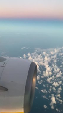 Gün doğumuyla, bulutlarla ve uçak motoruyla uçan uçak penceresinden görüntüle