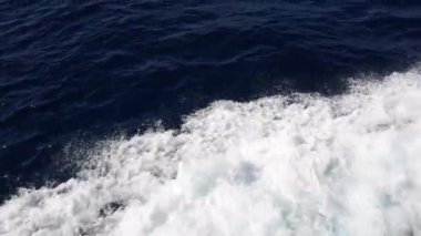 Dalgalar ve deniz köpüğü deniz sularında hareket eden yatın altına sıçrıyor.