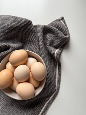Taze çiftlik tavuğu yumurtaları ve beyaz arka planda mutfak havlusu.