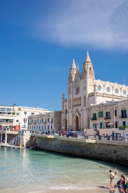 Balluta Körfezi plajı ziyaretçileri ve Sliema, Malta 'daki Balluta Kilisesi