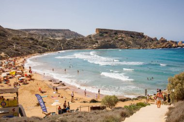 Malta 'daki Riviera halk plajında insanlar yüzüyor ve plajda uzanıyor.