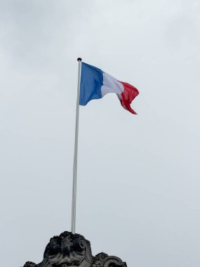 Rüzgarda dalgalanan Fransa bayrağı, gri kasvetli gökyüzünün arka planında. Avrupa ülkesinin siyasi sembolü.