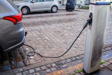 Elektrikli araba caddedeki şarj istasyonundan şarj ediliyor. Çevre koruma için ekolojik olarak temiz teknolojiler.