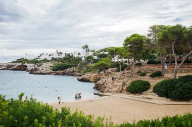 İspanya 'nın Mallorca adasındaki Cala d' Or köyündeki Cala Esmeralda plajının manzarasının keyfini çıkaran insanlar.