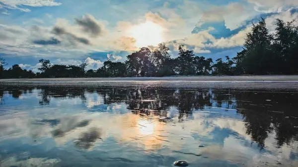 Bu Pantai Anak Air Kuantan Pahang sahilinde cazip bir günbatımı. Bu güzel manzara bulutlu bir günde akşam vakti çekildi ve deniz suyu görüntüyü simetrik bir kompozisyon oluşturarak yansıtıyor..