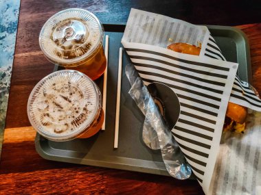 Perlis, Malezya - 21 Ocak 2024: İki buzlu çay ve tepsiye sarılı panini çizgili sığır eti.