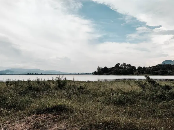 Yeşil çimenli dağın karanlık ve güzel manzarası ve Tasik Timah Tasoh, Perlis, Malezya 'da bulutlu mavi gökyüzü arka planıyla sakin bir göl..