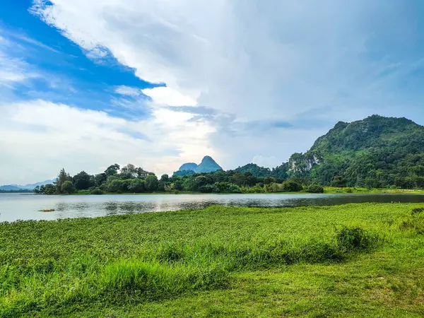 Yeşil çimenli güzel bir dağ manzarası ve Tasik Timah Tasoh, Perlis, Malezya 'da bulutlu mavi bir göl..