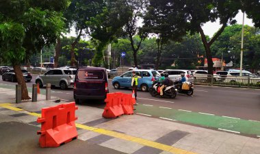 Kota Kasablanka alışveriş merkezinin önünde araçları olan kalabalık bir cadde ve alışveriş merkezinin güvenlik görevlisi alışveriş merkezinden ayrılan arabaları düzenliyor. Jakarta, Endonezya 'daki Kota Kasablanka alışveriş merkezinin önündeki yoğun ve yoğun trafik atmosferi, 21 Mayıs 2024.