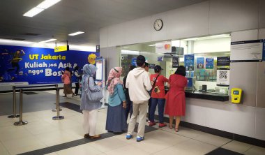 Yolcular MRT istasyonunun bilet gişesinden bilet almak için kuyruğa girdiler. Erkek ve bayan yolcular bilet gişesinde MRT istasyonunda kuyrukta bekliyorlar. Jakarta, Endonezya, 7 Temmuz 2024.
