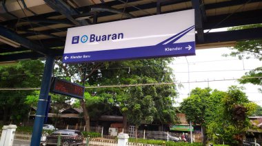 Tren istasyonu platformunun üzerindeki işaretler ve istikametler. Buaran İstasyonu 'nun beyaz ve mavi tabelaları. Banliyö tren istasyonu. Klender İstasyonu ve Klender Baru İstasyonu 'na yönlendirme işaretleri. Jakarta, Endonezya, 28 Nisan 2024.