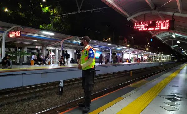 Gece Sudirman KAI istasyon platformunun atmosferinde bir güvenlik görevlisi nöbet tutarken. Platformu incelerken bir güvenlik görevlisi üniforması giyiyor. Jakarta, Endonezya, 23 Haziran 2024.