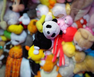 Diğer bulanık bebeklerin arasında sevimli siyah beyaz bir panda. Arka planda toplanmış bir grup oyuncak bebek. Bulanık bebekler. Sevimli panda bebeği.