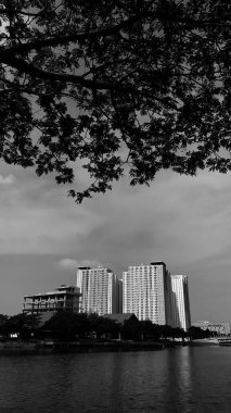 A beautiful black and white photo of a beautiful and serene lake in front of a magnificent apartment building, and its water reflects beautiful sunlight and shadows. Bekasi, Indonesia, October 11, 2024. clipart