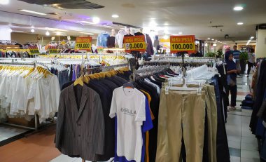 Alışveriş merkezindeki dükkanlar ITC Kuningan 'da indirimli ve özel fiyatlı günlük tişörtler sergiliyor. Müşteriler mağazaların vitrinlerine bakıp alışveriş yapmaya hazırlanıyorlar. Endonezya, Jakarta, 6 Ekim 2024.