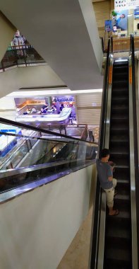 Bir adam, 6 Ekim 2024 'te, Jakarta' daki ITC Kuningan Endonezya alışveriş merkezindeki altın kuyumcusunun önünde dar bir yürüyen merdivende duruyor. Uzun süren salgın nedeniyle kapalı olan birçok dükkan görülebilir..