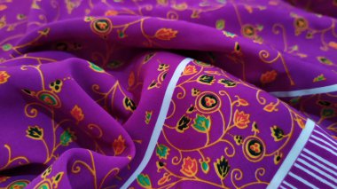 İnce ve pürüzsüz pembe bir kumaş. Ucunda küçük yeşil yapraklar ve güzel küçük çiçekler olan küçük bir kök motifle hafifçe katlanmış. Güzel bir arka plan ve doku..