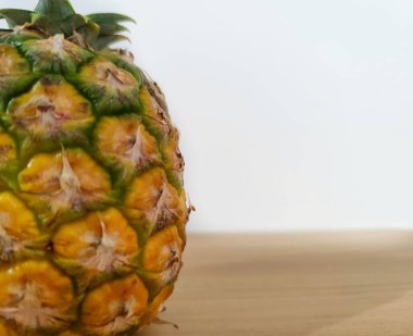 Sarı ananasın pürüzlü ve pullu dokusuyla kendine özgü tatlı bir tadı vardır. Yakın çekimde olgun küçük ananas, yarım, solda beyaz arkaplan ile izole edilmiş..