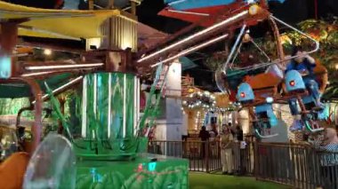Çocuklar ve aileleri lunaparkta uçan bir atlıkarınca bisikletine binerek eğleniyorlar ve heyecanlılar. Eğlence Dünyası Maceraları 'nda pervaneli bisikletle uçmak. Jakarta, Endonezya, 6 Nisan 2025.