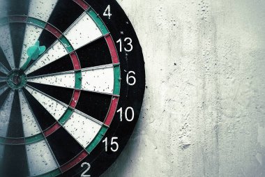 Dartboard yıpranmış bir duvarda asılı. Hedef oyun. Sık kullanılan oyunlardan kalma küçük delikleri olan dartboard. Dart tahtasının dokusu ve arkaplanı.