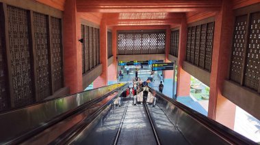 I Gusti Ngurah Rai Uluslararası Havalimanı 'ndaki asansörle inen yolcular. Bali, Endonezya. 15 Haziran 2025. Modern geleneksel dekorasyonla havaalanının giriş koridoru.