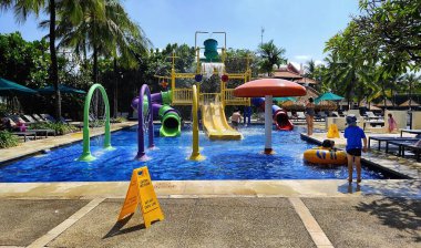 Çocuk havuzunda heyecan verici su oyunları ve çocukların mutlu oynadığı bir slayt tüneli yer alıyor. Badung, Bali, Endonezya, 16 Haziran 2025.