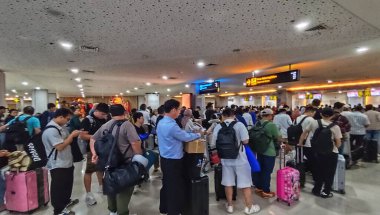 I Gusti Ngurah Rai Uluslararası Havalimanı 'nın gişelerinde kuyrukta bekleyen bir sürü yolcu var. Birçok gezgin elinde bavullarla kuyrukta bekliyor ve hareketli kalkış atmosferini de ekliyor. Bali, Endonezya, 2 Temmuz 2025.